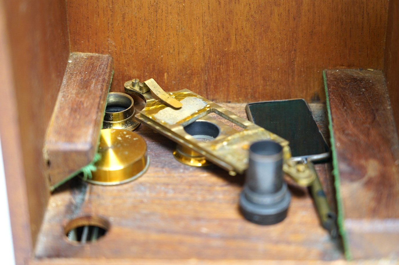 An unmarked late 19th century monocular brass microscope, in a fitted mahogany case with alternative lenses, a drawer for slides and other accessories, case 39cm high. Condition - fair to good